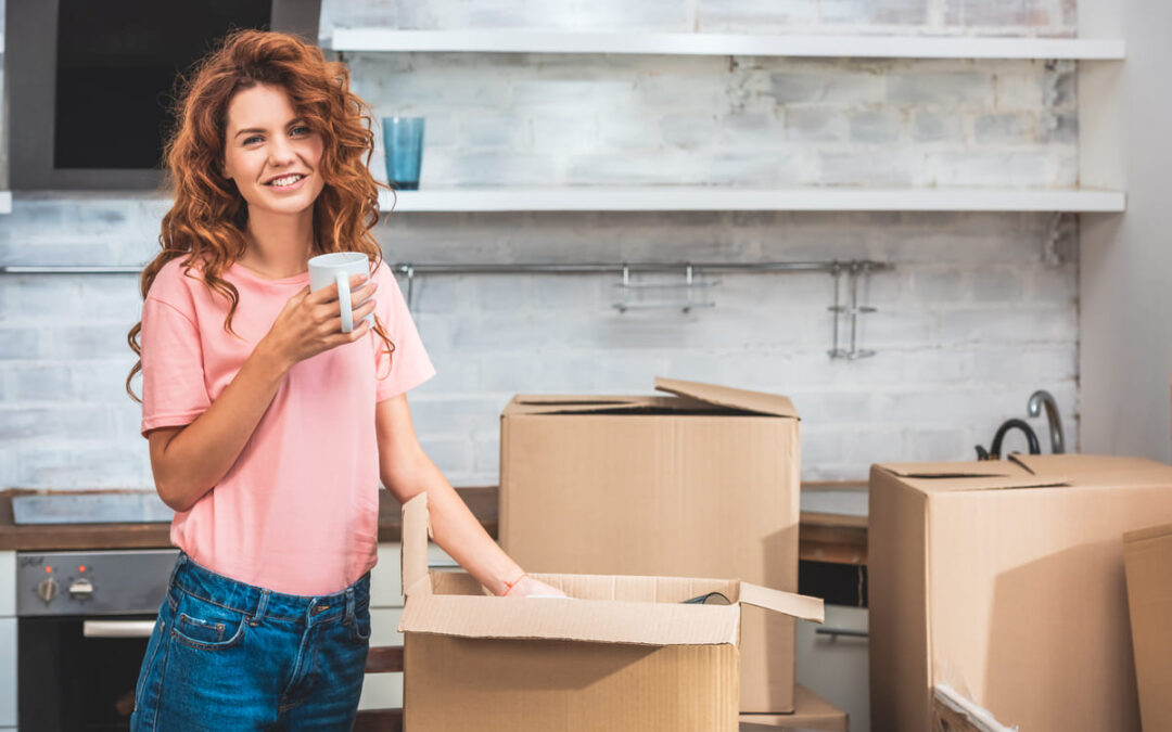 woman holding cup while unpacking boxes