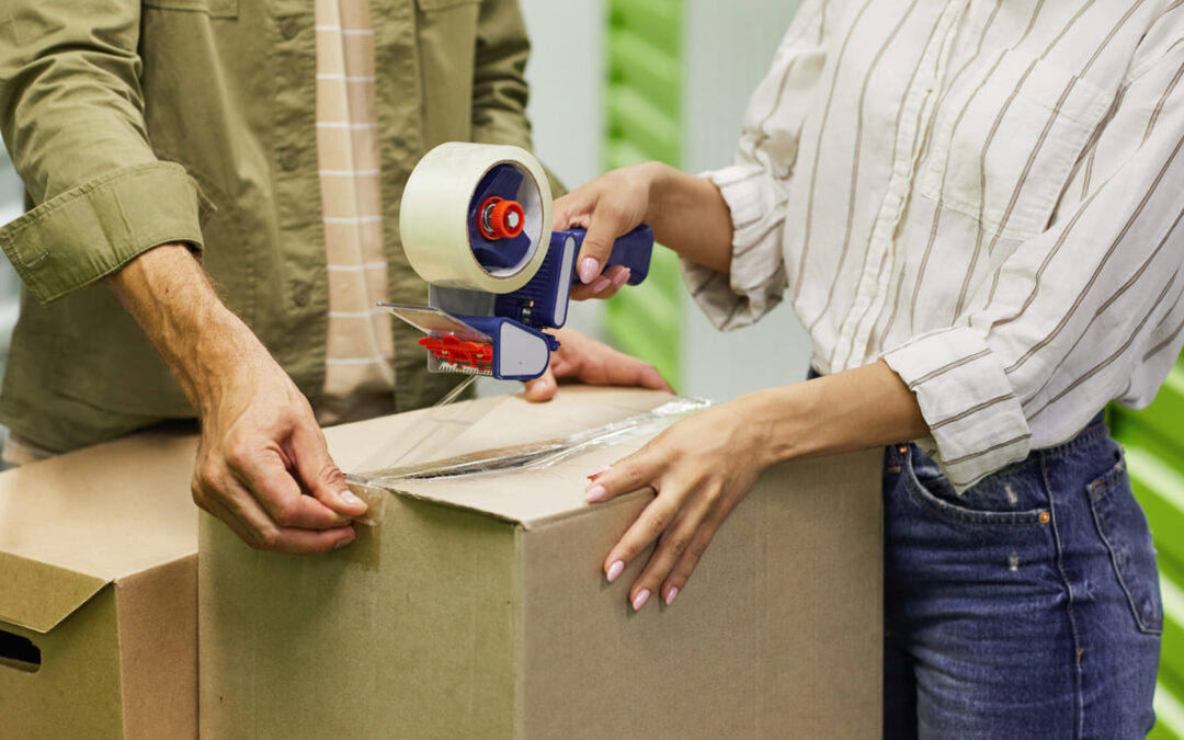 people closing a cardboard box with packing tape