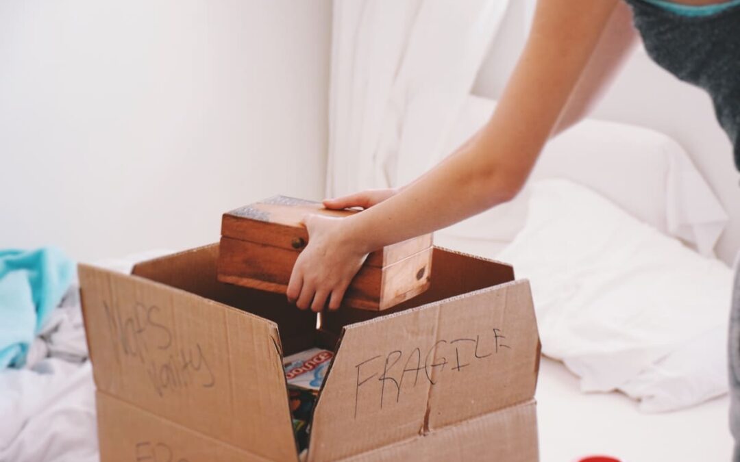 Girl packing a box with fragile items into cardboard box for moving